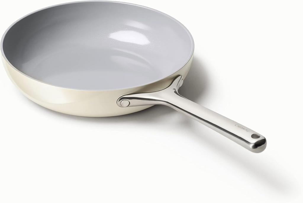 A Caraway ceramic nonstick fry pan with a sleek design, featuring a gray interior and a stainless steel handle, positioned on a white background.